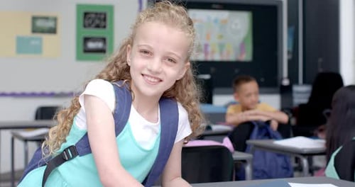 Caucasian girl smiles in a classroom at school, with copy space
