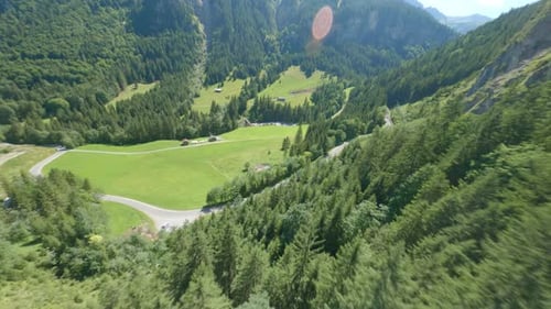 Aerial cinematography showing camper van parked on road amidst huge green mountains in Austria.