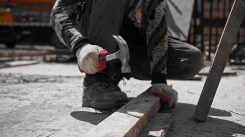 Construction Worker Hammers Nail into Wood