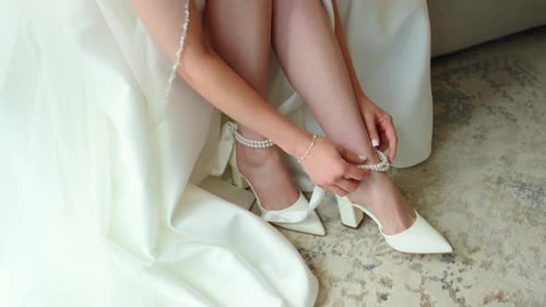 Bride Ties Ribbon on Stylish White Wedding Shoes