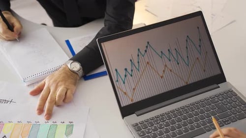 Büroangestellte arbeiten, indem sie sich Finanzdiagramme ansehen.