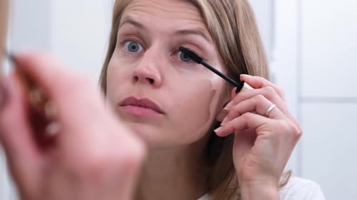 Woman Applies Mascara in Mirror for Beauty Routine