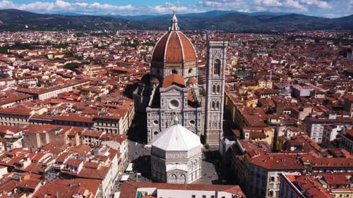 Aerial view of Cathedral of Santa Maria del Fiore flying and zooming in with city and mounatins on a