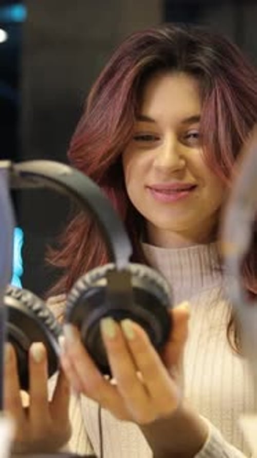 Vertical Video of a Young Positive Girl Choosing Headphones Closeup of a Young Positive Girl