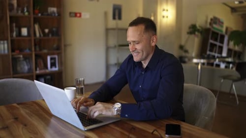 Smiling Businessman Working on Laptop Computer at Home Office