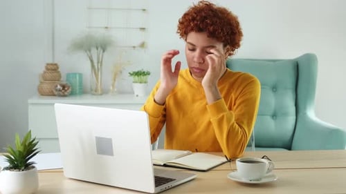 Woman Massaging Temples at Desk With Headache
