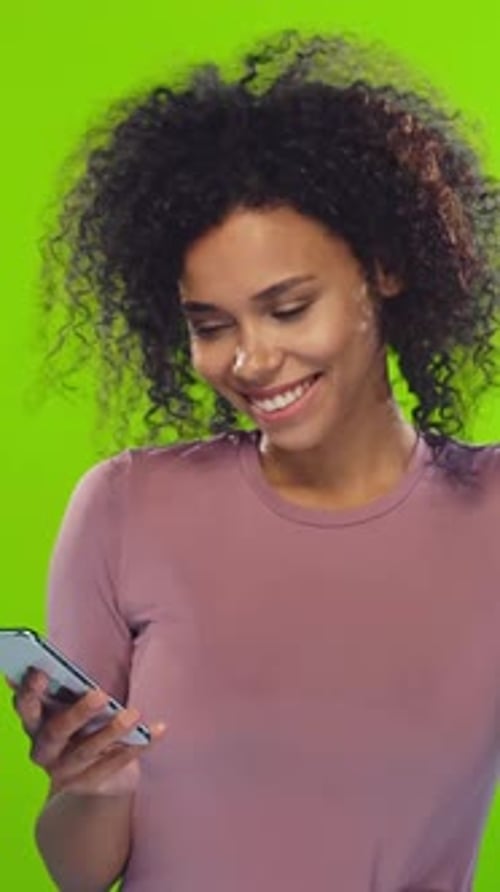 Femme souriante engageant son smartphone sur fond vert vif