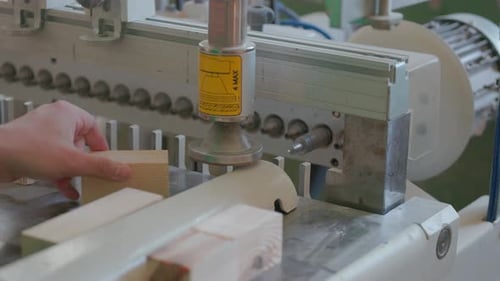 A man works with wood in a workshop. Working with wooden blanks. A man drills holes in wooden blanks