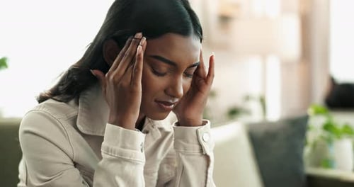 Headache, pain and Indian woman in home on sofa with anxiety, depression and fatigue
