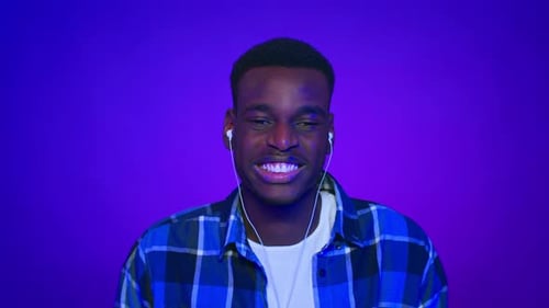 Happy Man Smiling and Wearing Headphones on Purple Background