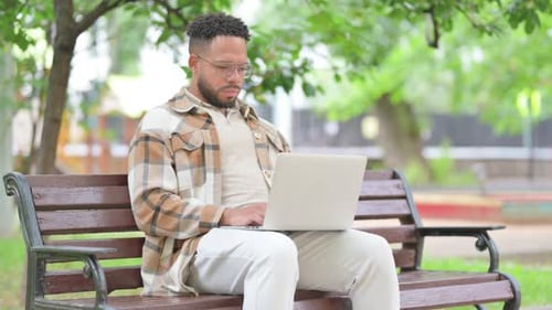 Hispanic Man Smiling with Laptop in Park
