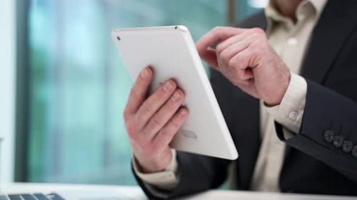 Close up of male hands holding digital tablet at desk at workplace in modern business office.