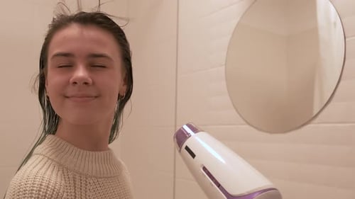 Woman Dries Hair in Bright Bathroom