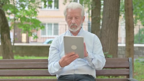 Senior Old Man using Tablet while Sitting in Park