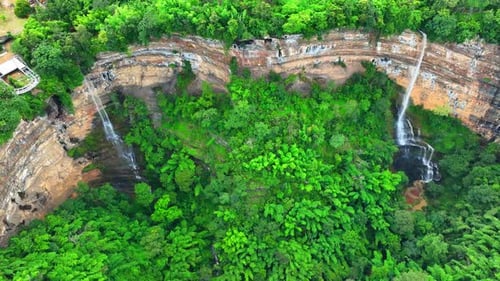 Drone captures majestic waterfall cascading from cliff.