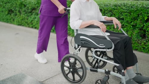 Old elderly disabled Asian patient and a nurse sitting in a wheelchair. Take a walk in the fresh