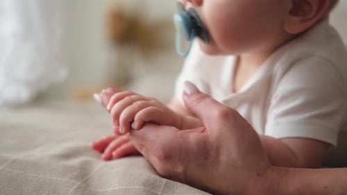 Baby Holding Hand of Caring Adult Indoors
