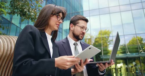 Side View of Two Successful Colleagues Man and Woman Having Outdoor Meeting Discussing Important
