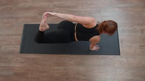 Beautiful Caucasian woman doing fitness on mat at home. Media. Top view of a girl performing