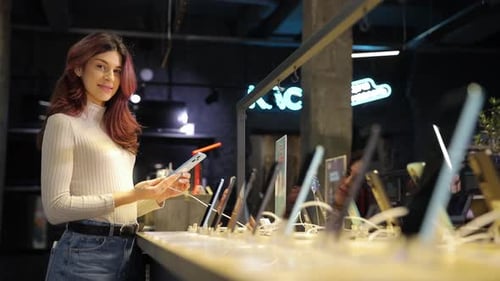 Woman Chooses New Smartphone in Store of Household Appliances Electronics and Gadgets