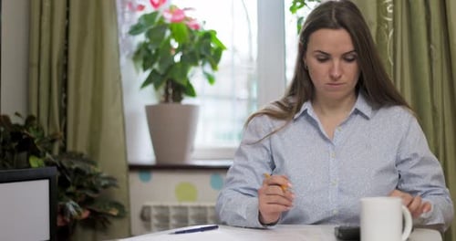 Mujer usando una calculadora para calcular las facturas domésticas en casa