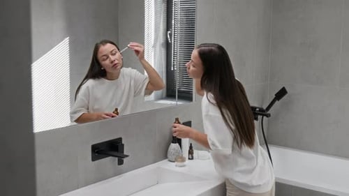 Woman Applying Serum in Modern Bathroom