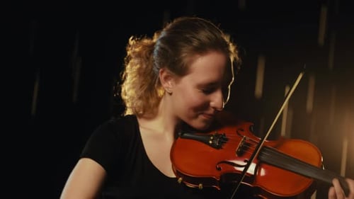 Young Woman Skillfully Playing Violin in Dark Studio