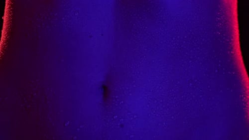 Closeup Shot of Beautiful Caucasian Woman Body Part Dancing in Neon Light Touching Tummy Area Smooth