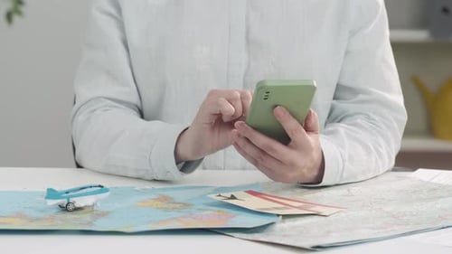 A Closeup of a Travel Agent's Hands Viewing Information on a Smartphone