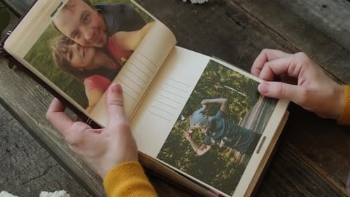 Concepto de impresión fotográfica: mujer hojea el álbum de fotos y mira las fotos que contiene