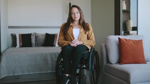 Young Woman in Wheelchair Indoors Looks at Camera