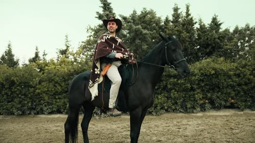 Cowboy sur un cheval noir dans le ranch