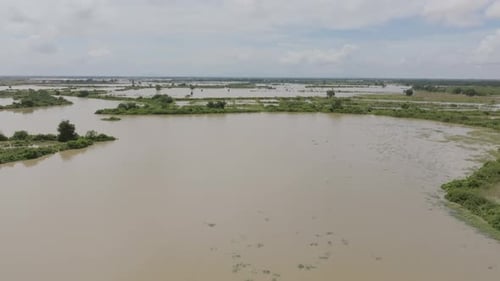 Wide aerial shot of flooded plains in Cambodia, with patches of green vegetation scattered between