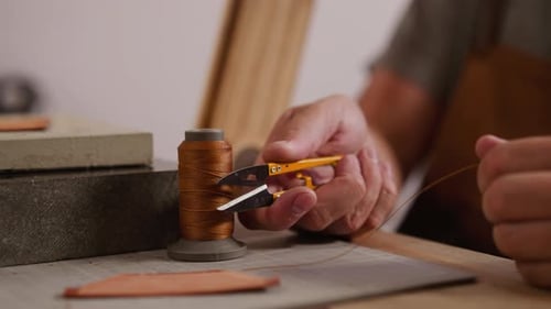 Tailor Cuts Waxed Thread with Scissors for Leather in Shop