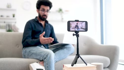 Arabian Man with Laptop Recording Video on Smartphone