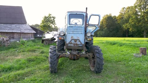 Moving towards close-up camera shot of old soviet tractor. Summer colors, sunny day. Green fields.Fa