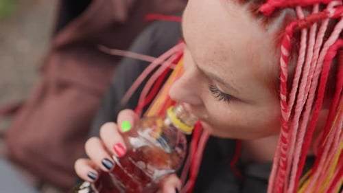 Close Shot of Woman with Braids Drinking Bottle Overhead Perspective Captures Woman with Colorful