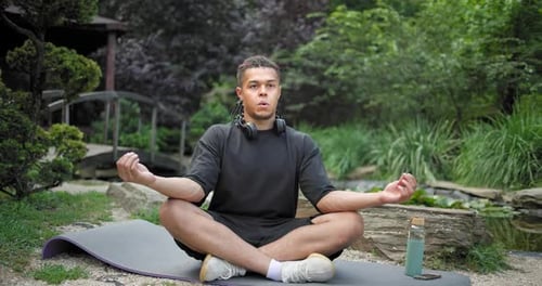 Young African American Spirituality Man Meditating Yoga Asana Sitting in a Park Outdoor