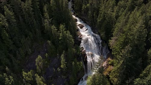 Majestic Waterfall Cascading Through Lush Green Forest In British Columbia Canada Aerial View