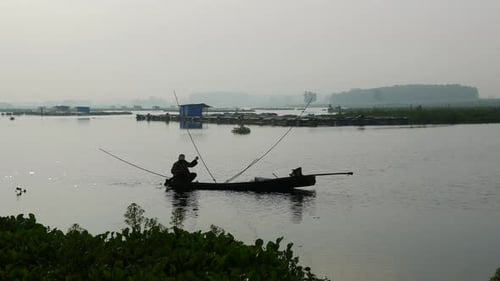 Aktivitäten südostasiatischer Männer, die auf traditionellen Holzbooten fahren, um Fische zu fangen