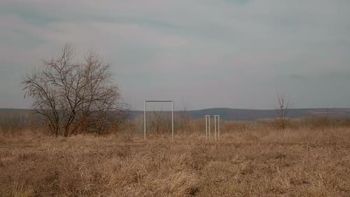 Deserted small sport field in poor village with some pull up bars left.