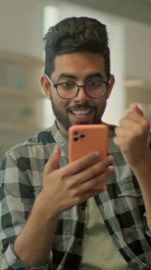 Young adult celebrates good news on mobile phone
