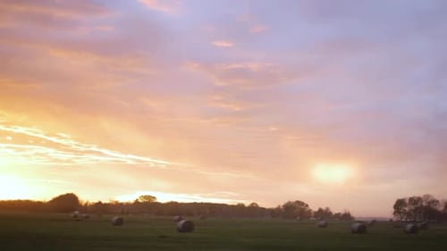 Colourful Sunset Over Field With Hay Bales