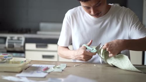 Young Adult Cutting Floral Fabric With Scissors