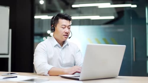 Man Works With Headset at Desk in Office