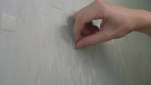 Hand Removing Transparent Wall Mount Strips from Wall
