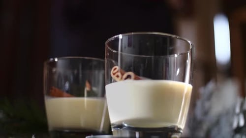 Front view of a man adding ground cinnamon to a traditional holiday drink Christmas eggnog