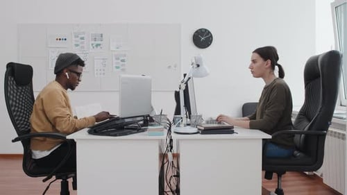 Ethnically Diverse Man And Woman At Work In Office