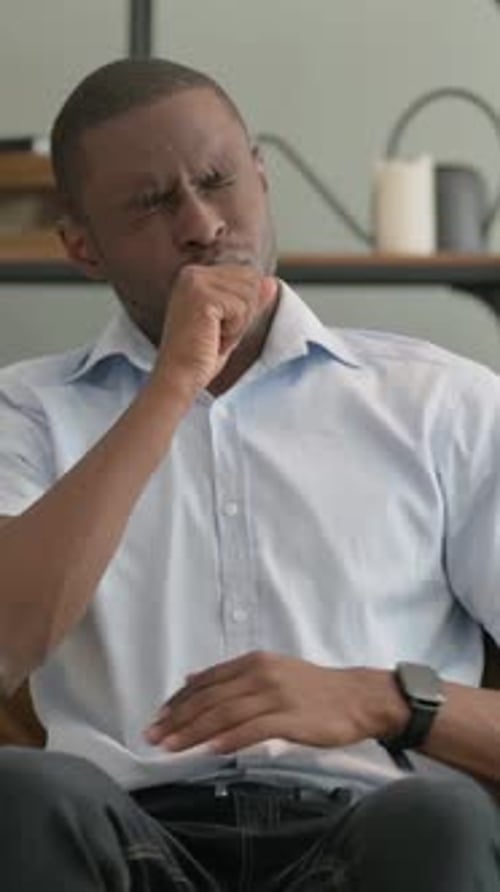 Vertical Video of Coughing African Man Sitting on Sofa at Home