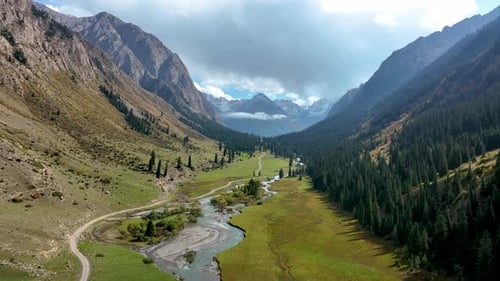 Epic drone flight down a vast, scenic mountain valley with a river